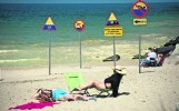 Znaki na plaży w Darłówku. Informują m.in. o zakazie skakania z falochronu