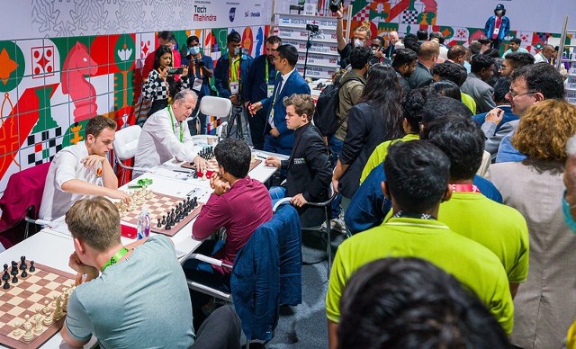Olimpiada Szachowa w Ćennaj. Przy szachownicy w oddali mistrz świata Norweg Magnus Carlsen (z prawej)