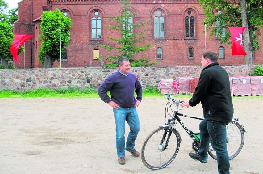 Maciej Mostowy i ks. Dariusz Leman (z rowerem) na placu,...
