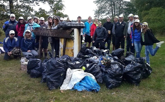 Uczestnicy akcji wraz z &#8222;owocami&#8221; kilkugodzinnej pracy - workami wypełnionymi śmieciami.