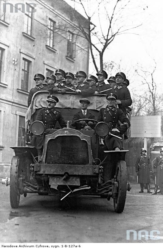 Grupa policjantów stojących na samochodzie przed akcją,...