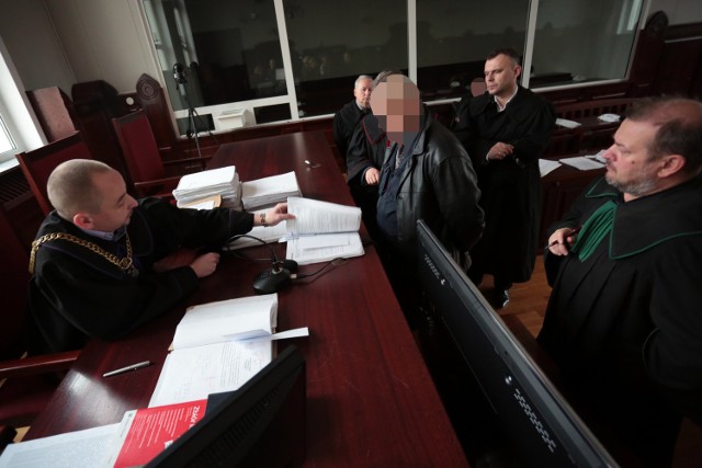 Świadek Marian S. oraz obrońcy oskarżonych przy stole sędziowskim w czasie okazania dokumentów ze Straży Gminnej.