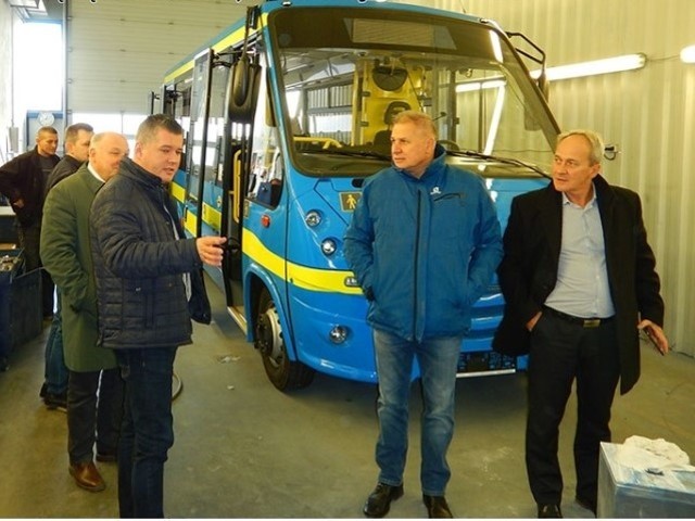 Urzędnicy z Andrychowa w fabryce autobusów. Do miasta trafią takie pojazdy jak ten w tle, ale w innym kolorze