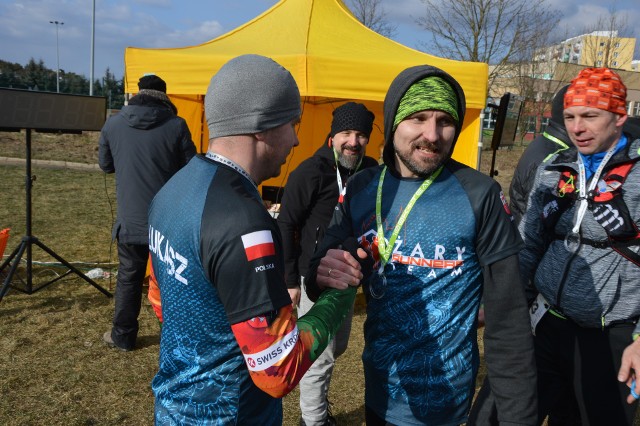 Zielonogórski ultramaraton ma to do siebie, że nigdy nie wiadomo, co może spotkać zawodników na trasie. Zwłaszcza, że biegnie ona głównie leśnymi ścieżkami. Uczestnicy wystartowali punktualnie o godzinie 6 rano. Na zewnątrz panowała wówczas temperatura -7 stopni Celsjusza. Postanowiliśmy sprawdzić, co słychać na mecie. Jak przewidywali synoptycy wraz z upływem dnia nad regionem zerwał się nieprzyjemny wiatr, który utrudniał zmagania uczestników zawodów oraz znacząco obniżał odczuwalną temperaturę. Przekraczając linię mety na zwycięzców czekały piękne, szklane medale, ciepły posiłek oraz co nieco do picia. Wybuch radości po przekroczeniu przez niektórych linii mety był bezcenny. Pokonane 103 kilometry zrobiły swoje, a uczestnicy po raz kolejny przekonali się, że sukces w takiej imprezie jest na wyciągnięcie reki. Wszystkim finiszującym serdecznie gratulujemy!IV Ultramaraton Zielonogórski Nowe Granice - WYSTARTOWALI O 6 RANO [GALERIA nr 1, 2, 3]