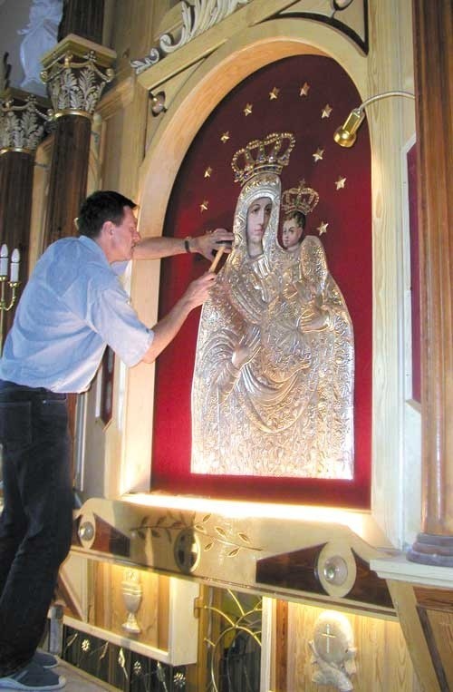 Historyczny moment - zawieszenie przez Jarosława Kolca, pracownika Akademii Sztuk Pięknych w Łodzi, na obraz Madonny z Dzieciątkiem Jezus posrebrzanej sukni, którą sam wykonał