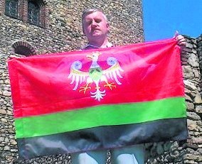 Zbigniew Matuszczyk z flagą Zagłębia Dąbrowskiego na tle jednego z symboli tego regionu, zamku piastowskiego w Będzinie