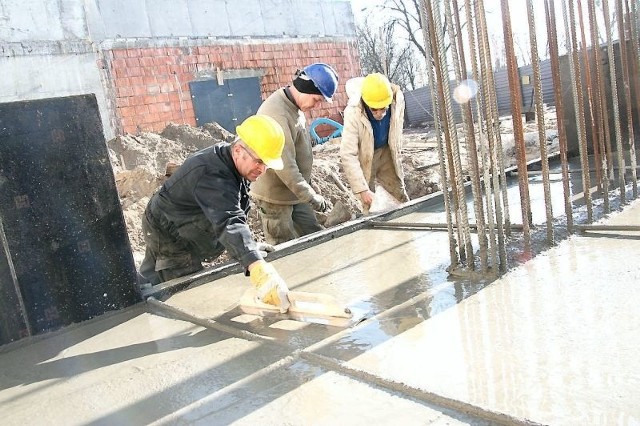Pracownicy firmy "Alstal&#8221; wyrównują tzw. stopę fundamentową pod słup, który podtrzymywać będzie dach nad częścią trybun