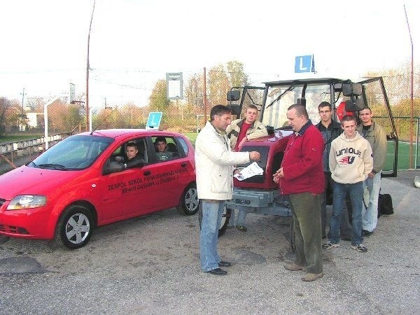 Na zdjęciu dyrektor Piotr Sadowski  przekazuje kluczyki od nowo  zakupionego samochodu osobowego i  ciągnika instruktorowi nauki jazdy  Szymonowi Gocowi.
