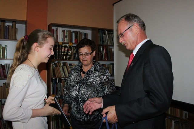 Natalia Jakubczak, laureatka konkursu plastycznego, odbiera nagrodę z rąk burmistrza Andrzeja Cieśli i dyrektorki MBP Wandy Drabikowskiej.