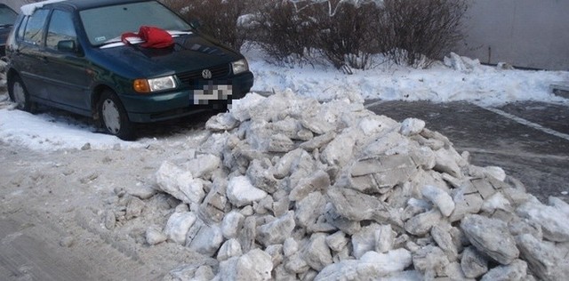 Hałdy śniegu z chodniku wysypano tam gdzie parkują samochody.