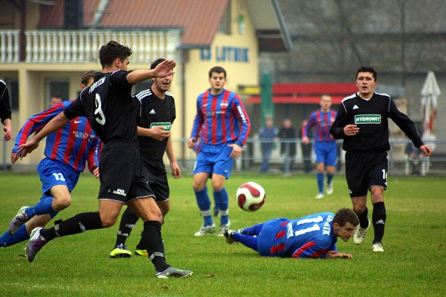 Lotnik Kryspinów - Iskra Klecza Dolna (29.10.2011 r). Sebastian Pamuła (nr 11) zatrzymany przez obrońców Iskry. Piłkę wybija Michał Drechny (nr 9), z prawej Kamil Glanowski