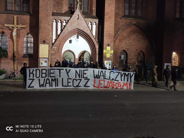 Kibice Gryfa Słupsk z transparentem pod kościołem
