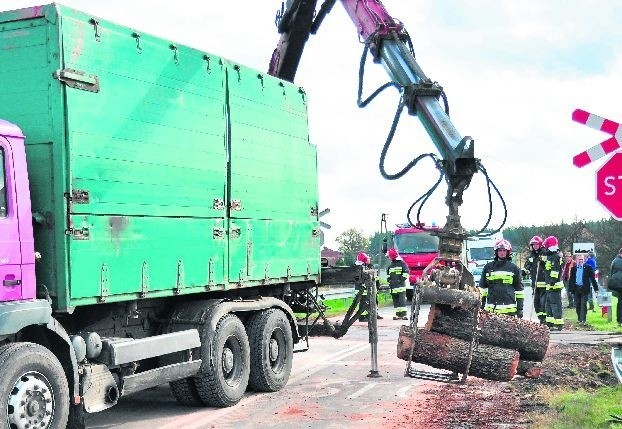 Wskutek zderzenia z przyczepy wysypało się przewożone drewniane kloce. Na miejsce ściągnięto inny samochód z ładowarką, by móc załadować rozrzucony towar.