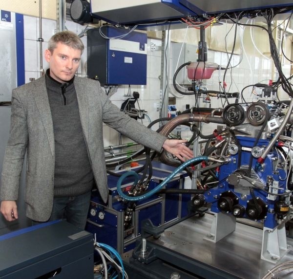 Tomasz Skrzek, pracownik naukowy Instytutu Eksploatacji Pojazdów i Maszyn prezentuje testowy silnik spalinowy poddawany bardzo różnym próbom.