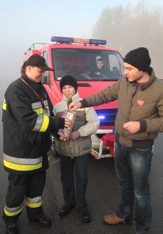 Magdalenie Żak z Ochotniczej Straży Pożarnej w Ćmińsku do orkiestrowej puszki wrzucają datki Mariusz Gaworek z Borkowa i Dominik Mazurek z Samsonowa.