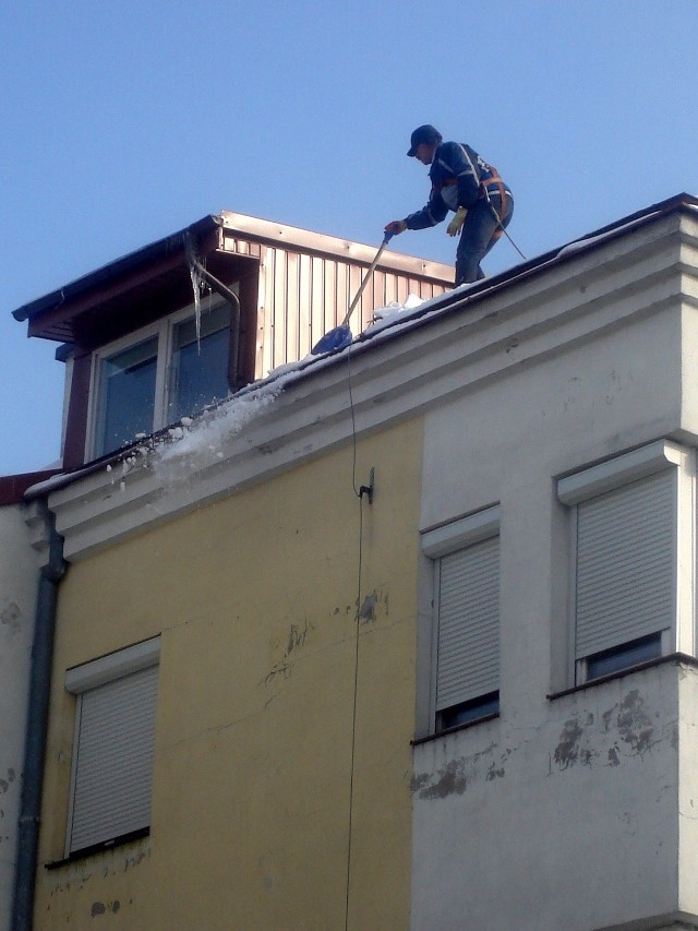 Odśnieżanie dachu budynku na ulicy Curie Skłodowskiej w Radomiu.