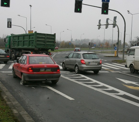 Czerwony opel skręca w lewo. Obok niego skoda na pasie na wprost, a przed nią ciężarowy samochód, który też skręca, choć nie powinien. Wkrótce służby miejskie uregulują ten stan wprowadzając możliwość jazdy w lewo z dwóch pasów.