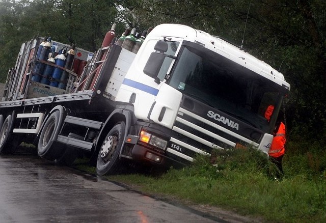 Koła ciężarówki ugrzęzły w miękkiej ziemi na poboczu.