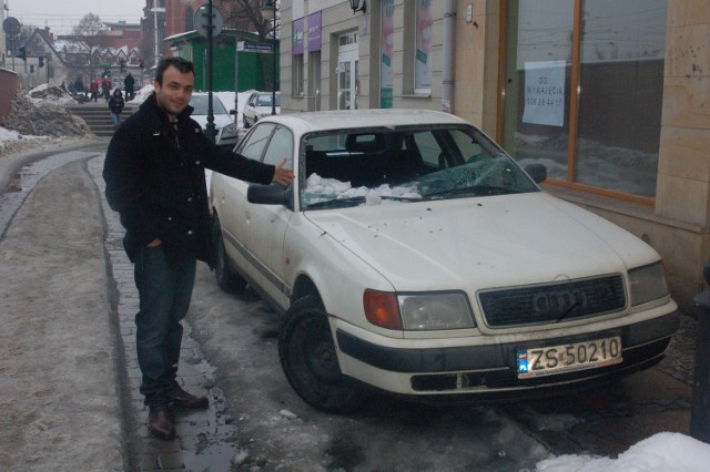 Pan Jan przy uszkodzonym samochodzie, w którym spadający śnieg wybił przednią szybę.