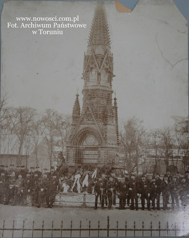 „Pomnik wojacki” w Toruniu. Przed nim weterani i płotek zbudowany w 1898 roku, a za nim plac, na którym Gustaw Ackermann  sprzedawał 120 lat temu rury i koryta glinkowe