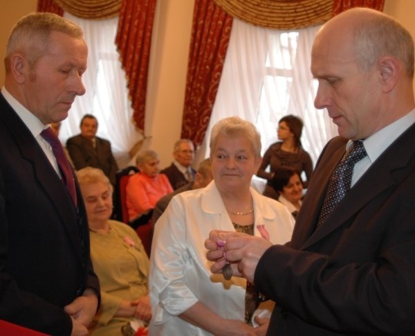 Burmistrz Jarosław Tkaczyński wręcza medale Janinie i Janowi Golcom.