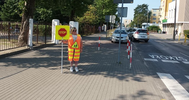 Pani Justyna Mlewska przeprowadza dzieci przez przejście dla pieszych na ruchliwej ulicy Bażyńskich przy Szkole Podstawowej nr 10