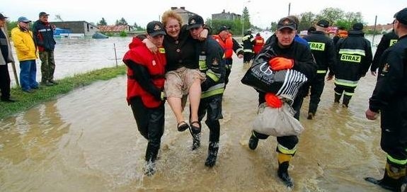 Z zalanaego domu strażacy przywieźl łódką kobietę.