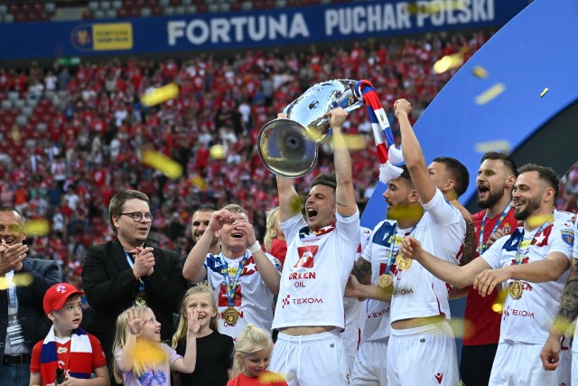 Uradowani piłkarze Wisły wznoszą do góry główne trofeum dla zdobywcy Pucharu Polski