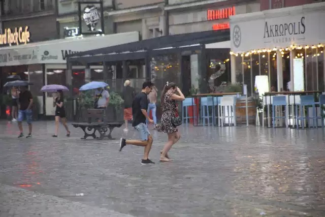 Tłum ludzi spacerujący po wrocławskim Rynku, podczas ulewnego deszczu uciekał do pobliskich restauracji i pod każde możliwe zadaszenie