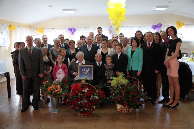 Anna i Kazimierz Czerwińscy wraz z gośćmi podczas jubileuszu 60-lecia. W rękach jubilatki haftowany prezent od wnuczki Anny Czerwińskiej.