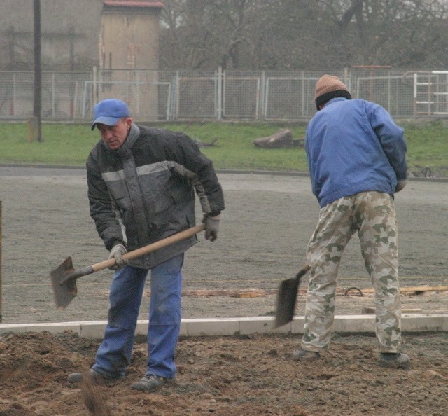 Robotnicy pracują przy budowie boiska bez względu na pogodę.