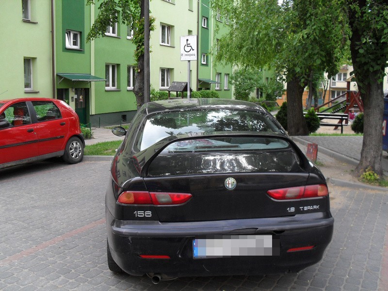 Alfa romeo zaparkowane na dwóch miejscach.