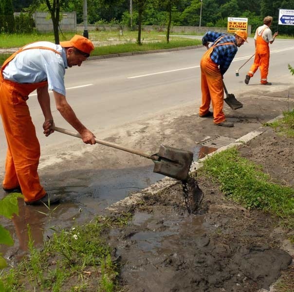Drogowcy z Zarządy Dróg Powiatowych w Stalowej Woli usuwają błoto z okolic studzienki kanalizacji deszczowej.