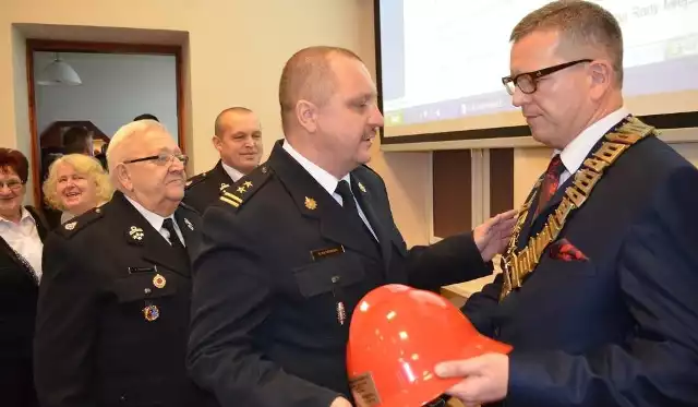 Grzegorz Rutkowski, komendant powiatowy straży pożarnej, wręcza hełm strażacki Robertowi Luchowskiemu - właśnie zaprzysiężonemu burmistrzowi Żnina.
