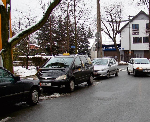 Po jednej stronie drogi parkują samochody