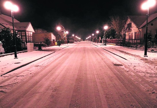 Oświetlona ulicznymi latarniami ulica Lipowa na osiedlu Charzewice w zimowej scenerii