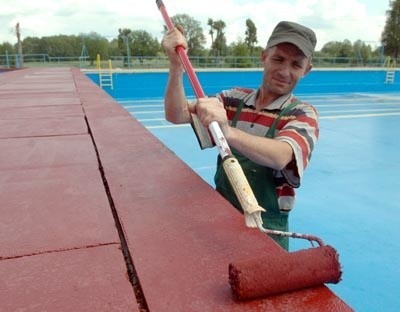 Aleksander Kiruszok maluje nieckę odkrytego basenu na terenie Ośrodka Sportu i Rekreacji. Obok, na razie, nie wyrośnie kryte kąpielisko.