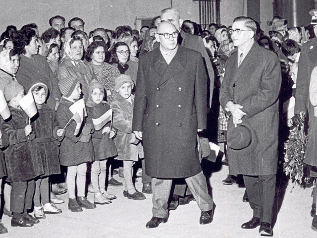 Aleksander Zawadzki, ówczesny  przewodniczący Rady Państwa (w środku, z kapeluszem w dłoniach) witany przez pracowników i szpaler dzieci z biało-czerwonymi flagami 