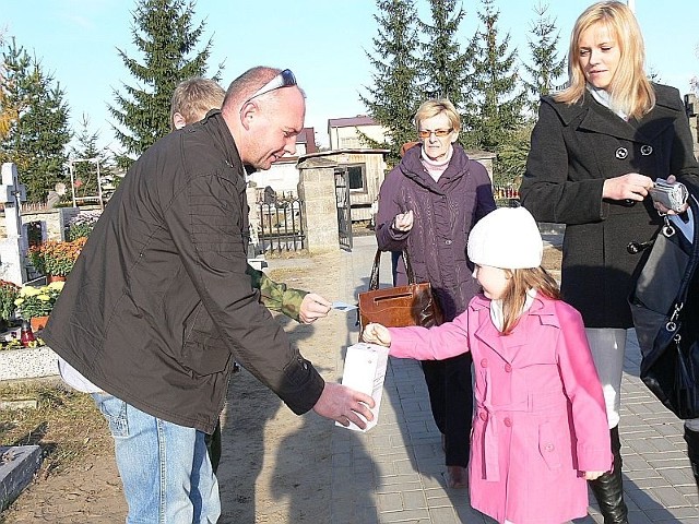 Martyna Jaworska, która z rodzicami odwiedziła bliżyński cmentarz, wrzuca datek do puszki. W Bliżynie zbierano na budowę cmentarnych alejek.