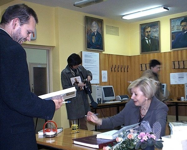 Joanna Siedlecka podpisuje swoje książki będące w  posiadaniu Rejonowej Biblioteki Publicznej w Szubinie.  Towarzyszy jej dyrektor placówki Mirosław Rzeszowski.