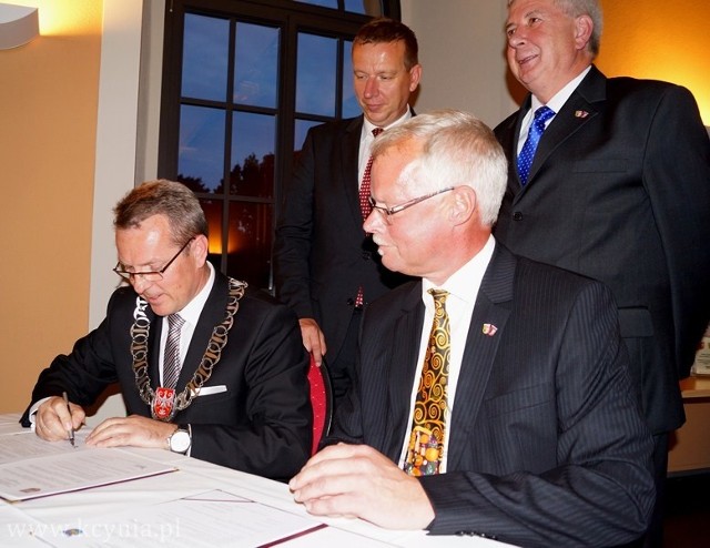 Podpis pod umową składa Piotr Hemmerling, obok burmistrz Bodo Broszinski. Z tyłu stoją starostwie: Nakła i Elbe- Elster