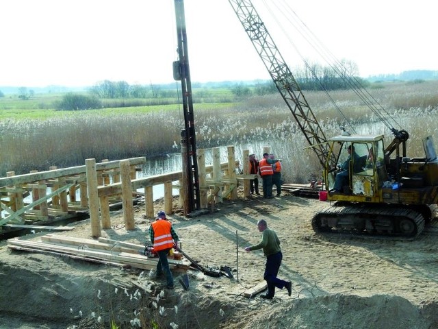 Na placu budowy nad rzeką praca wre. Robotnicy postawili już drewniany szkielet mostu objazdowego.