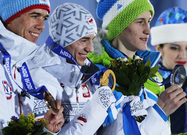 Kamil Stoch (w środku) cieszy się po odebraniu pierwszego złotego medalu olimpijskiego