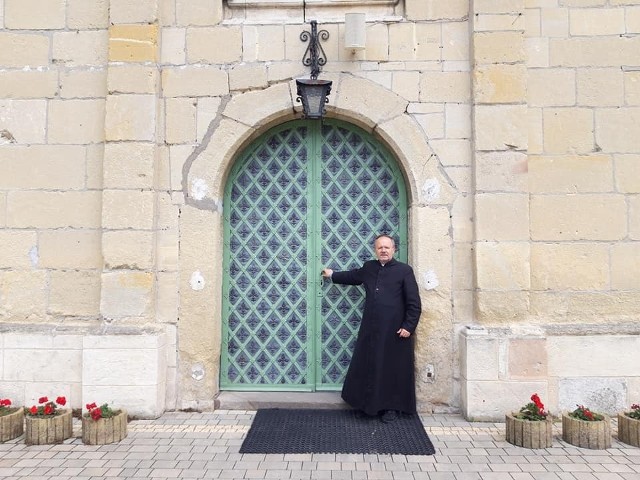 Na zdjęciu ksiądz proboszcz  Marian Fatyga przy odnowionych drzwiach głównych.