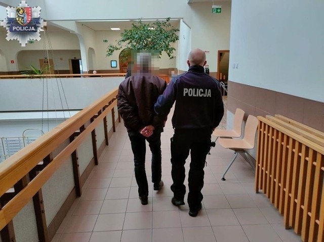 Policjant prowadzi jednego z mężczyzn zatrzymanych w Kielcach