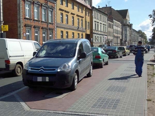 Ścieżka koło apteki Na schodkach zablokowana przez furgonetkę oraz ścieżka koło kina zastawiona przez samochody. 