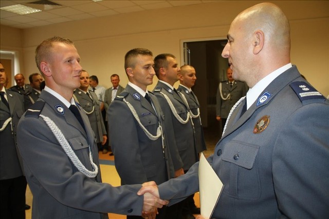 Zastępca komendanta wojewódzkiego świętokrzyskiej policji Rafał Kochańczyk (z prawej) wręcza nominacje na wyższe stopnie policyjne.