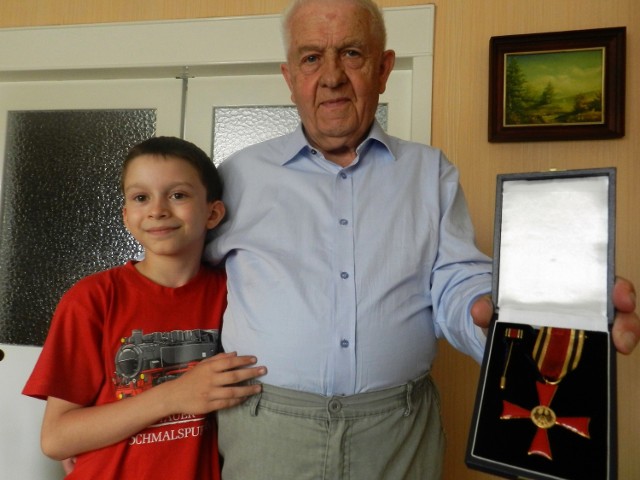 Joachim Niemann, były wieloletni dyrektor biura VdG, prezentuje Federalny Krzyż Zasługi. Razem z nim z odznaczenia dziadka cieszy się wnuk Krzysztof.