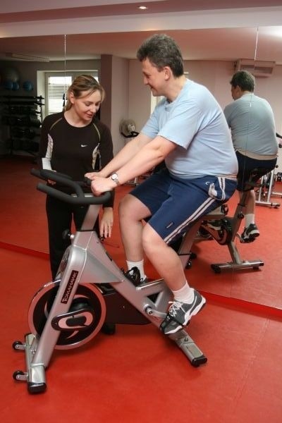 Olga Chaińska instruuje pana Artura jak prawidłowo ustawić rowerek treningowy.