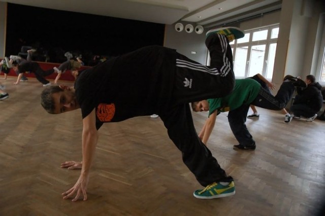 Michał Plewniak z Broken Glass2 (na pierwszym planie) prezentuje uczniom szkółki 2w1, jak prawidłowo wykonuje się podstawowe figury taneczne.